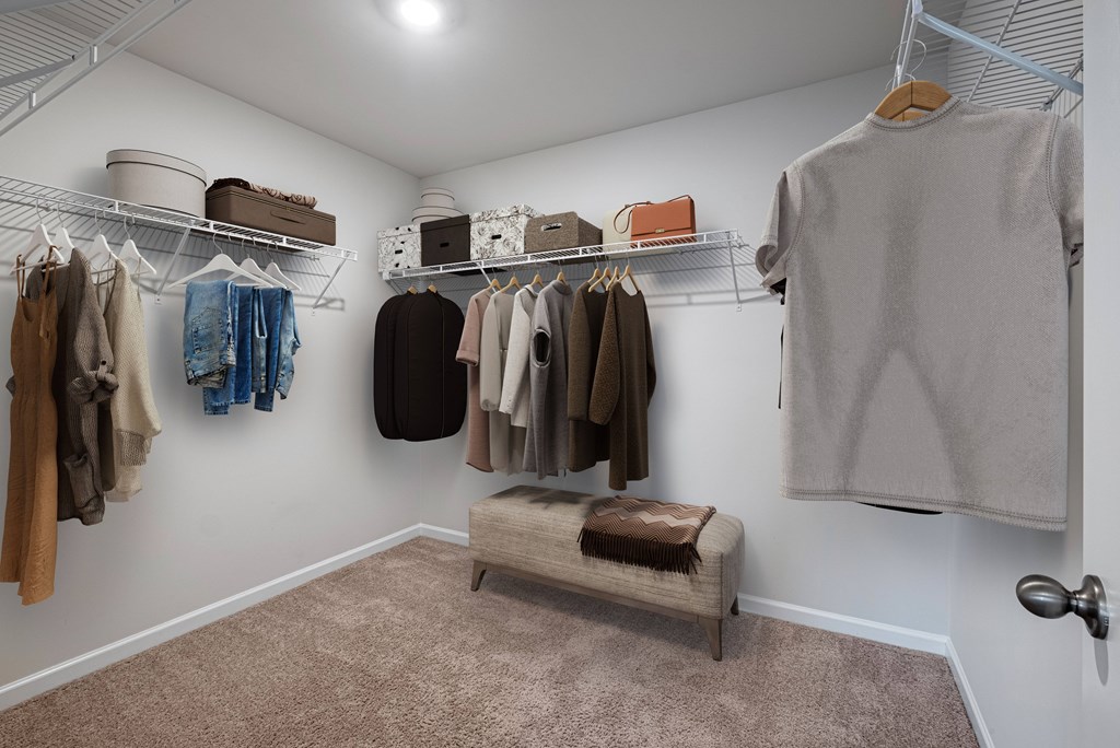 a closet with clothes hanging on a rack and a bench