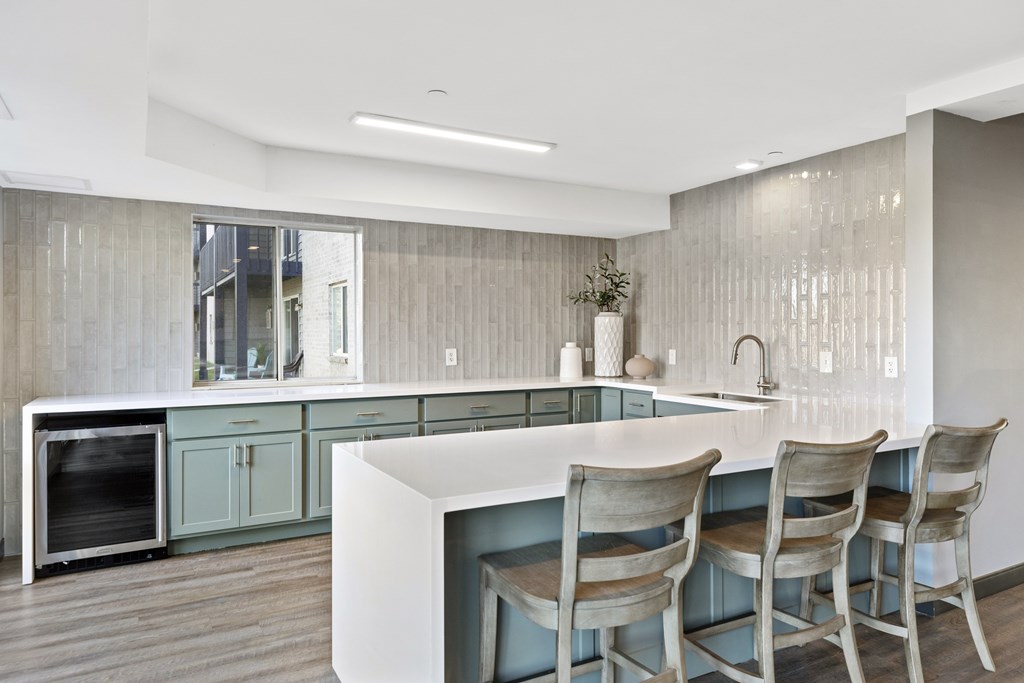 a kitchen with blue cabinets and a counter with three chairs