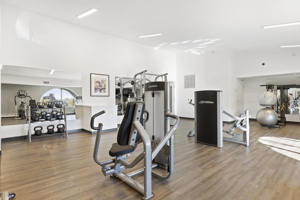a gym with cardio equipment and weights on a wooden floor