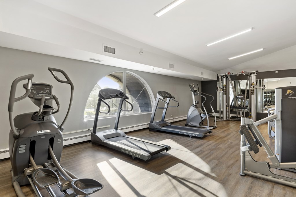 a gym with treadmills and other exercise equipment on a wood floor