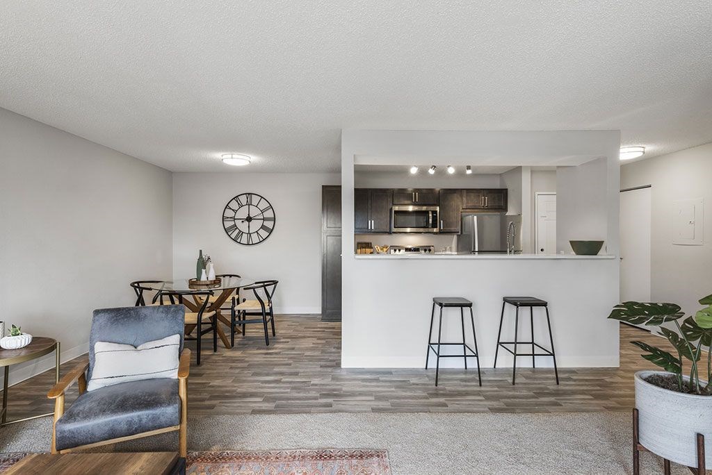 a living area with a kitchen and a bar with stools