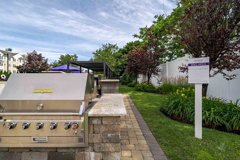 A stainless steel grill with a yellow sticker on it is on a patio.
