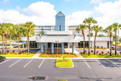a building with palm trees in front of a parking lot