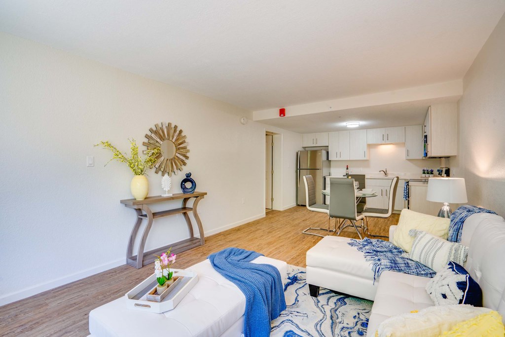 a living room with white couches and a dining room table and a kitchen