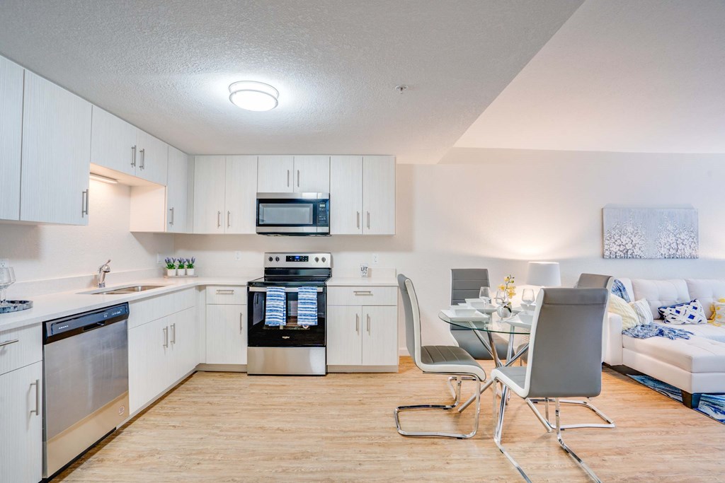 a kitchen and living room with white cabinets and a table and chairs