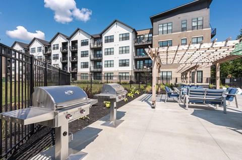 One-Bedroom Apartments in North Indianapolis, IN - North End Apartments - Outdoor Grilling Station With Stainless Barbecue Grills, Pergola Seating, and Apartment Buildings In View.