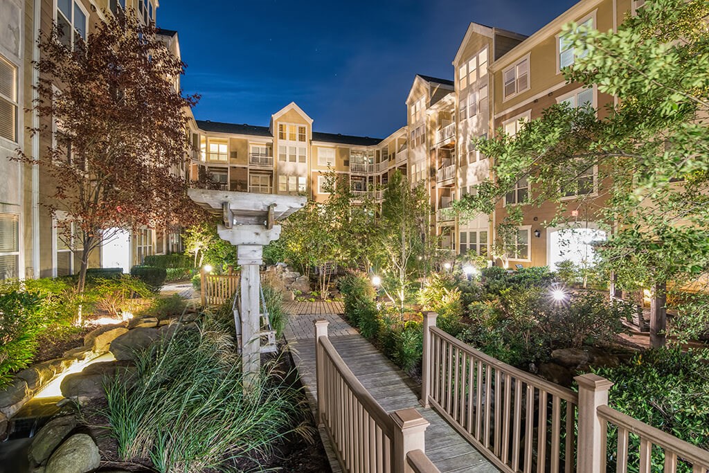 a view of a garden with a bridge and buildings at night