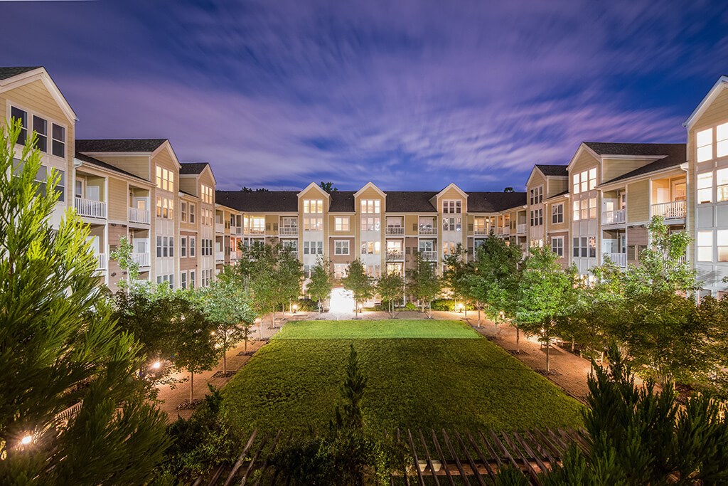 an aerial view of an apartment complex at night with a green courtyard