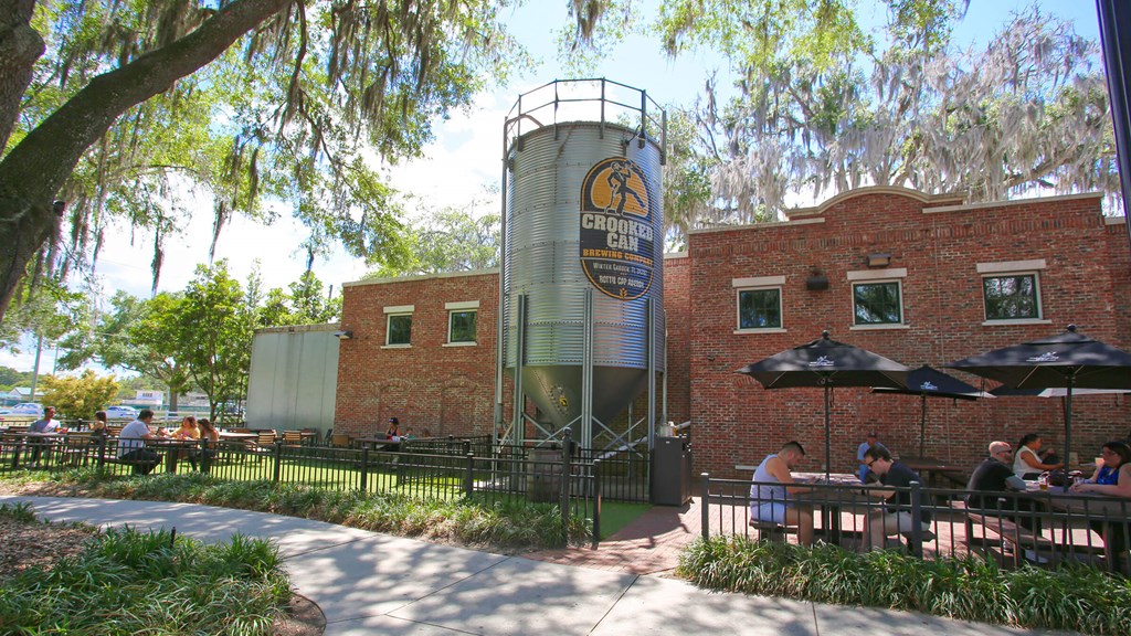 people sitting at tables outside of a brick building with a water tower