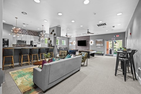 A living room with a grey couch and a kitchen area in the background.