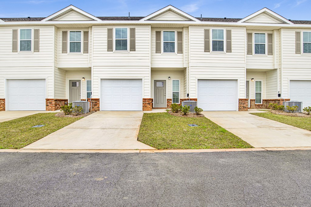 a white house with two garage doors on a sidewalk
