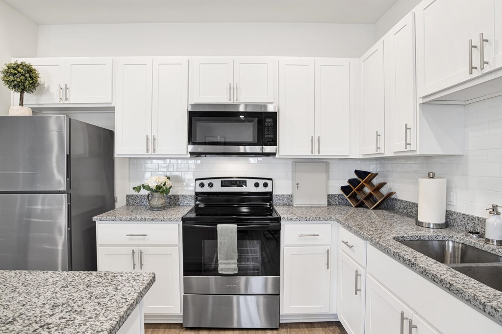 a white kitchen with stainless steel appliances and granite counter tops