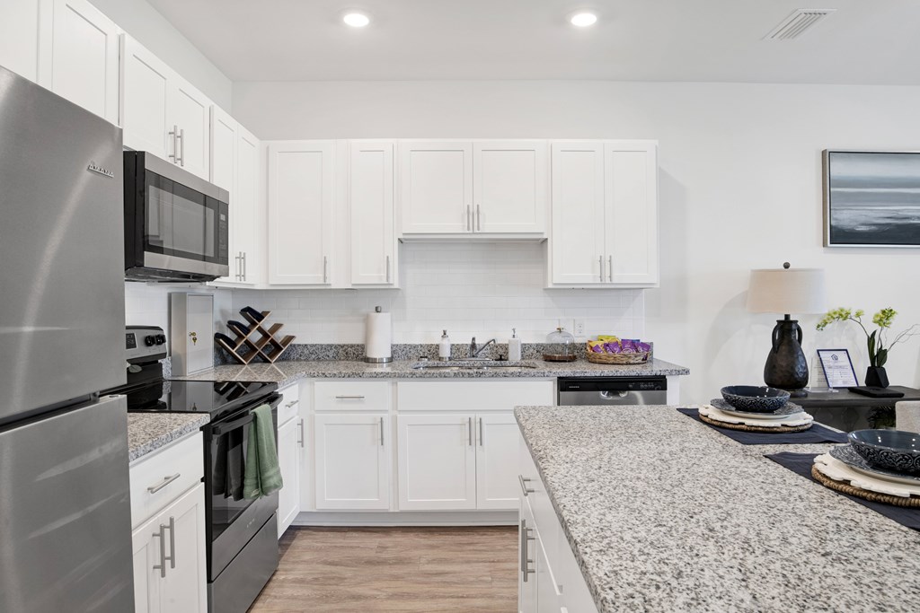 a kitchen with granite counter tops and white cabinetry
