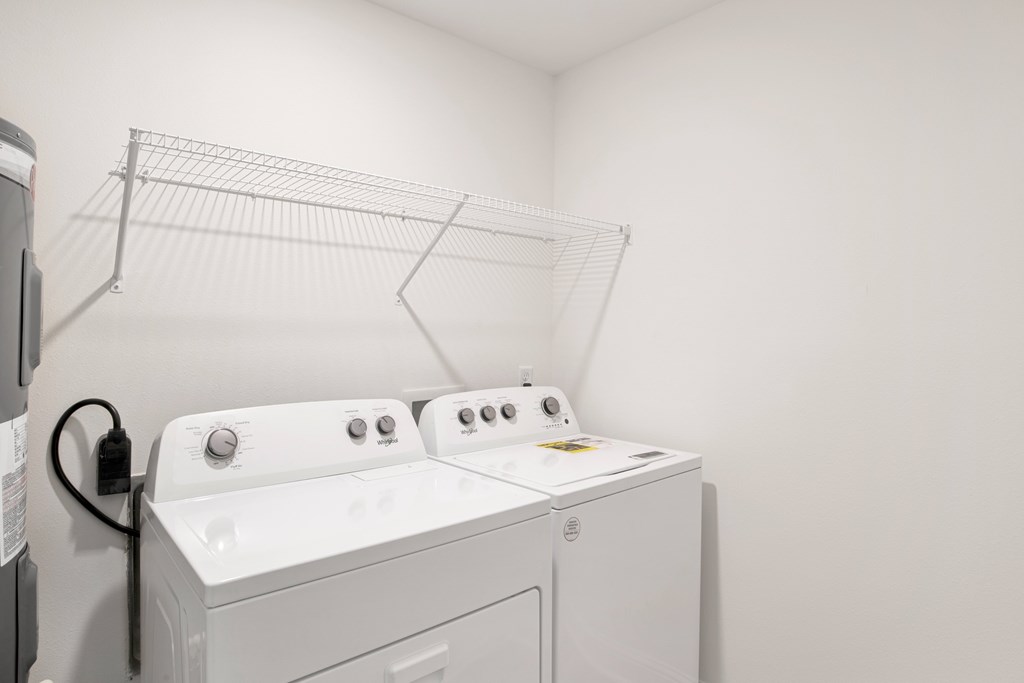 a washer and dryer in a room with a white wall and a shelf