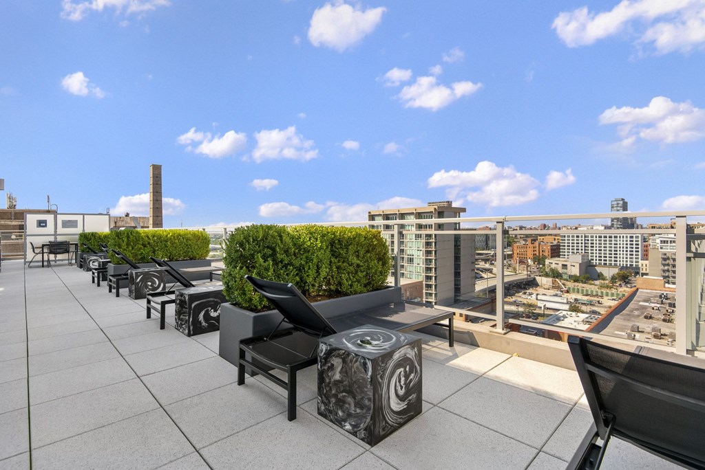 a rooftop terrace with furniture and a city in the background