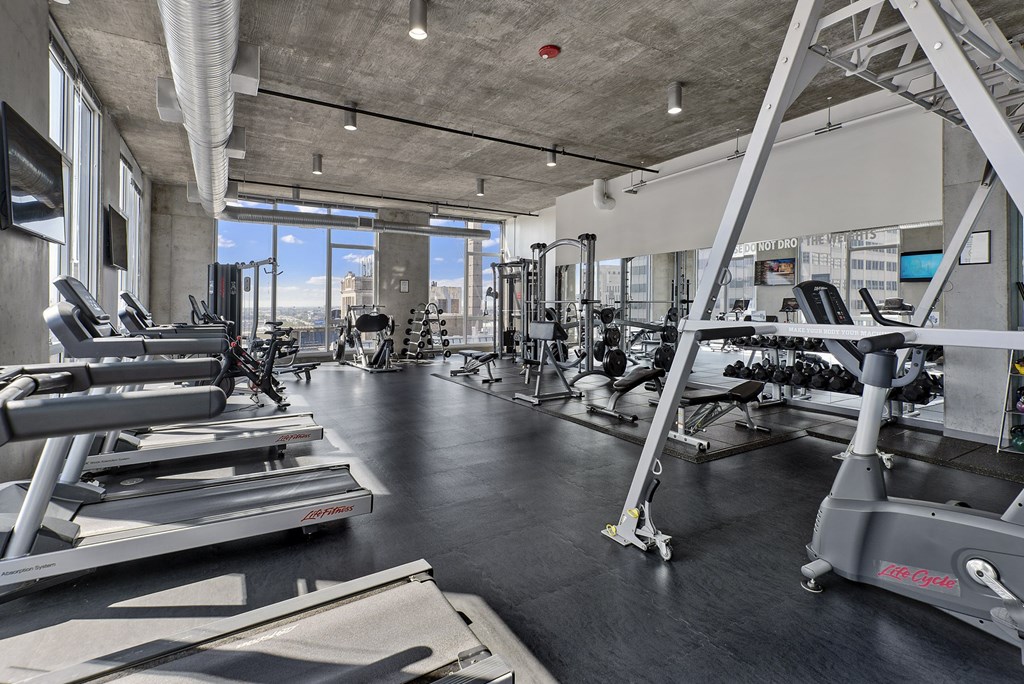 a gym with weights and cardio machines and a window
