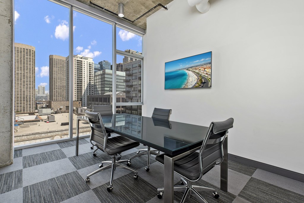 a conference room with a glass table and chairs and a view of the city