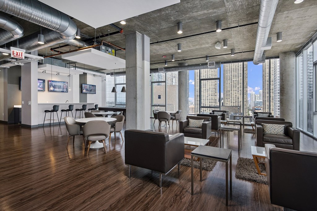 a lounge area with chairs and tables and a view of a city