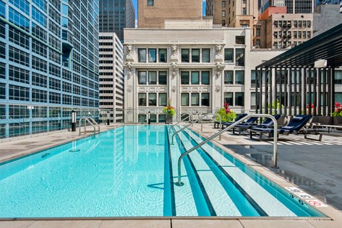 A swimming pool with a blue tinted water in the middle of a city.