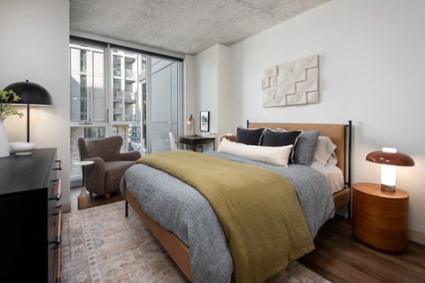 A bedroom with a large bed and a chair.