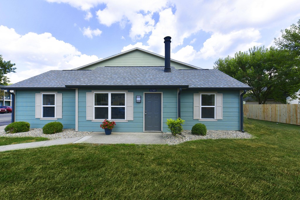 a blue house with a blue roof and a lawn