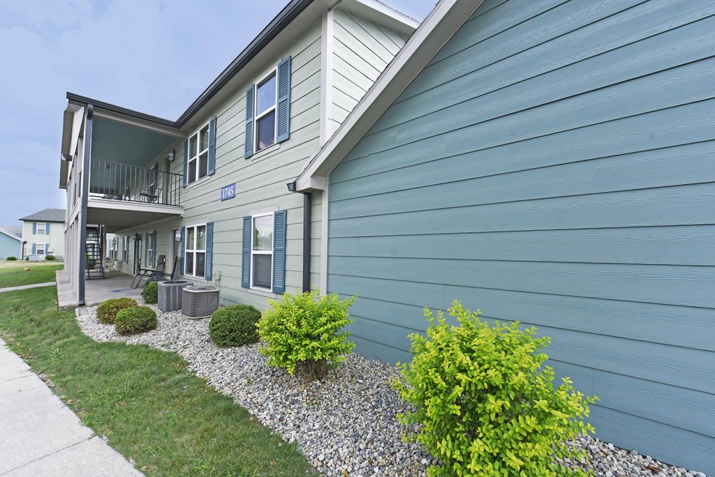 the front of a blue house with a sidewalk and green plants