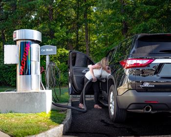 a woman pumping gas into a car at a gas station