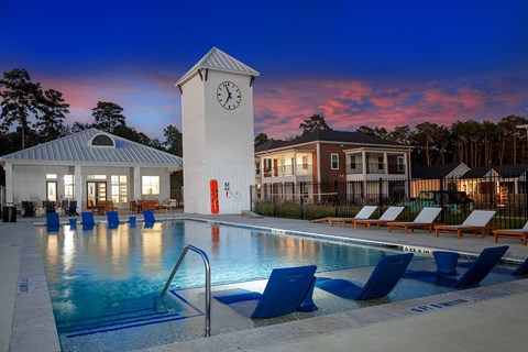 a swimming pool with a clock tower at night