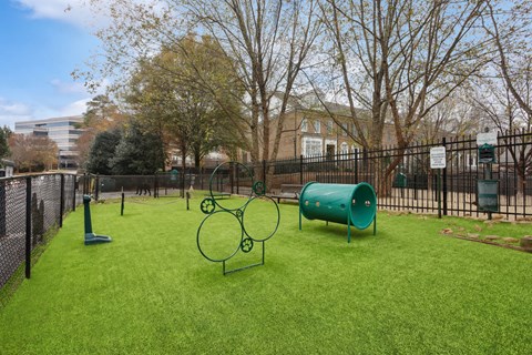 A playground with a green slide and a green barrel.