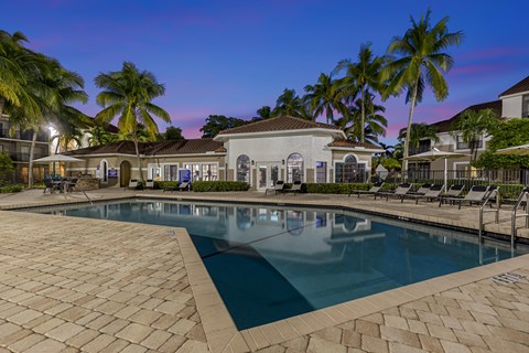 a large swimming pool with lounge chairs and umbrellas in front of a house