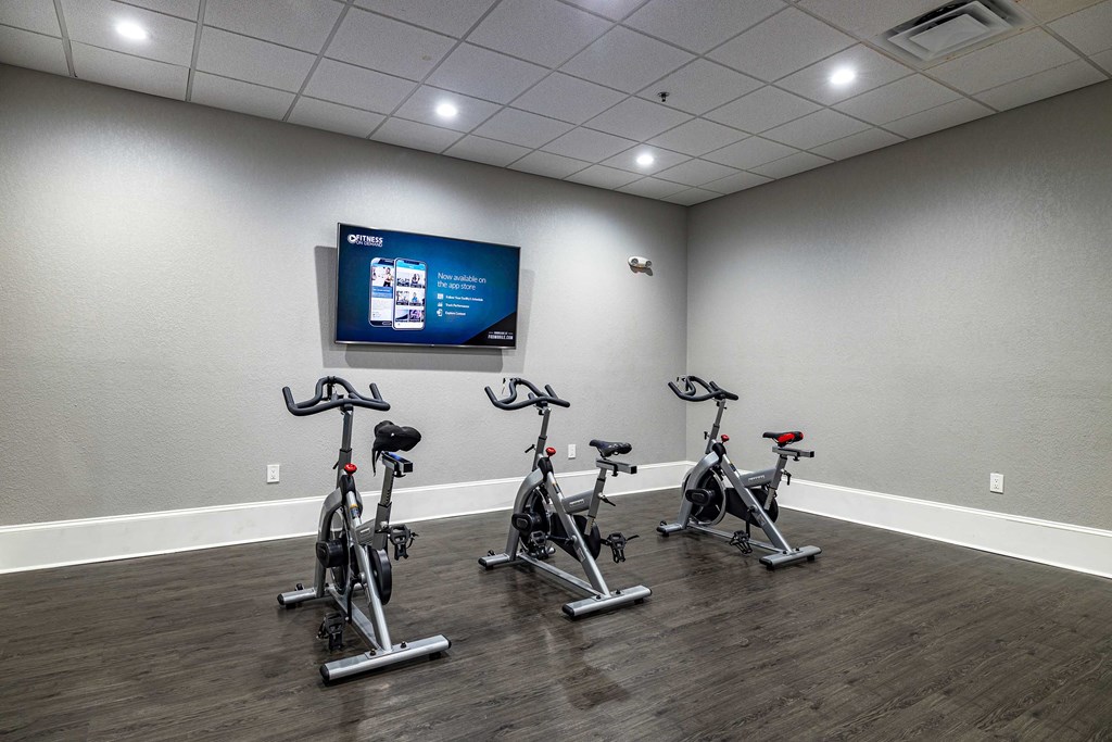 a fitness room with exercise bikes and a tv
