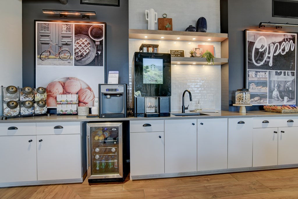 a kitchen with white cabinets and a counter with coffee machines