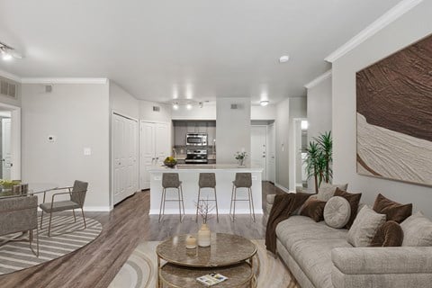 a living room with a couch and a table in front of a kitchen