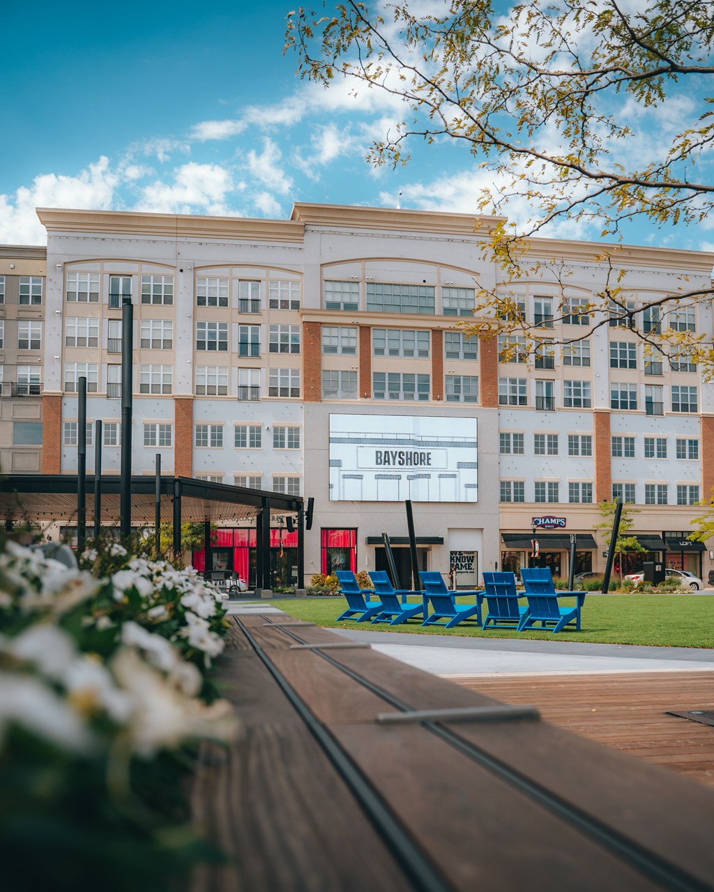 a large white building with blue chairs in front of it at The Bayshore Place Apartments in Glendale, WI