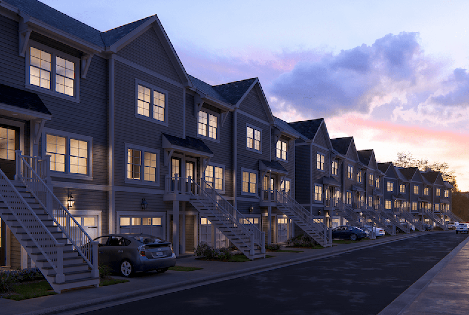 A row of houses with cars parked in front.