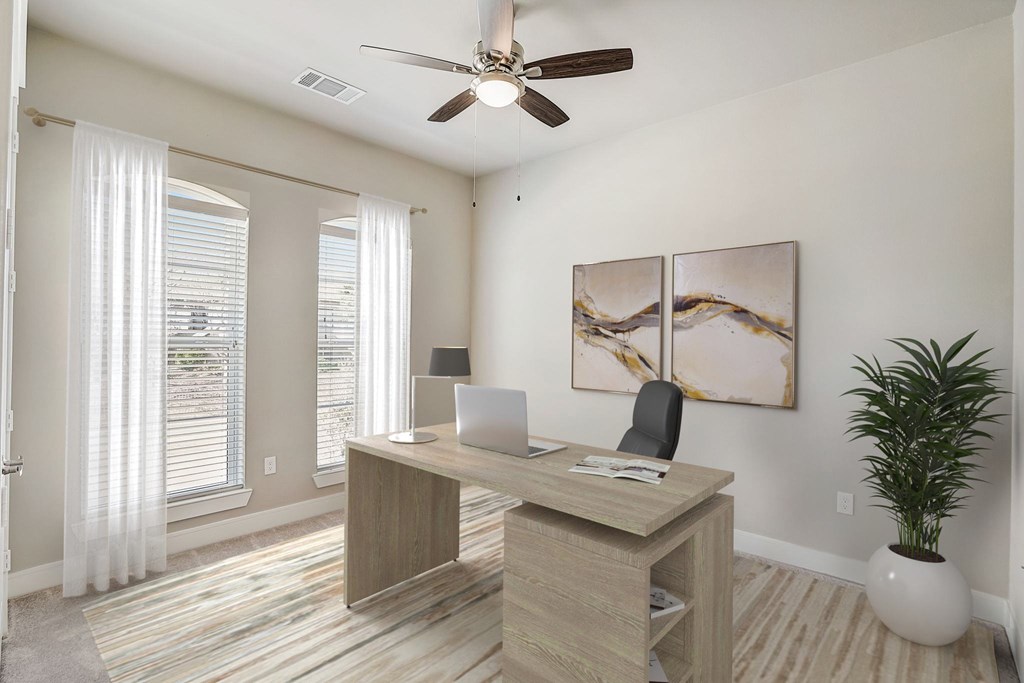 an office with a ceiling fan and a desk with a laptop