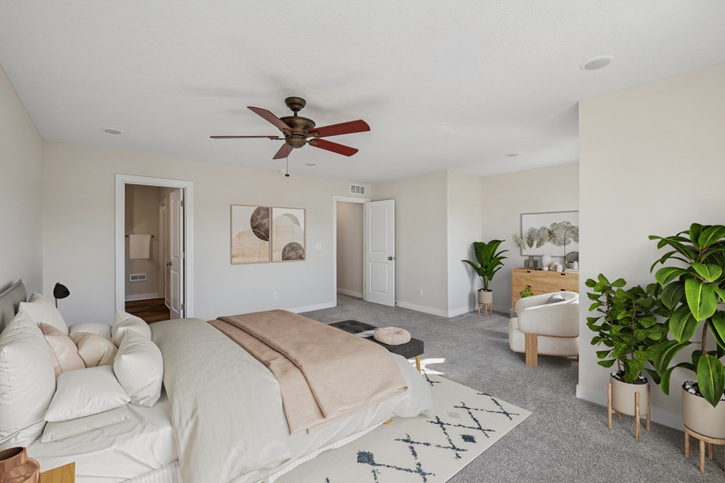 A bedroom with a bed, a chair, a potted plant, and a ceiling fan.