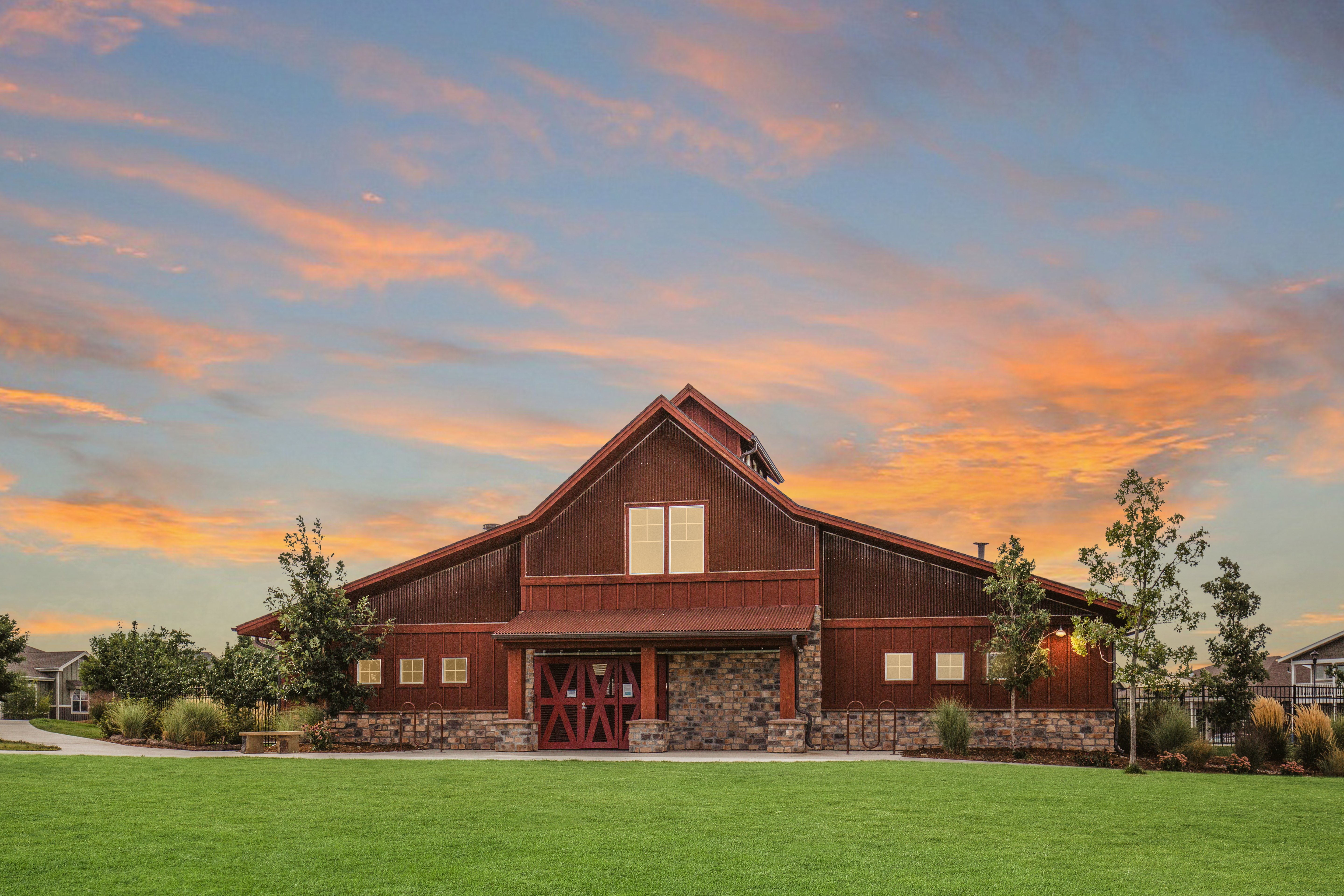 A barn-like building with a red door and a stone wall in front.