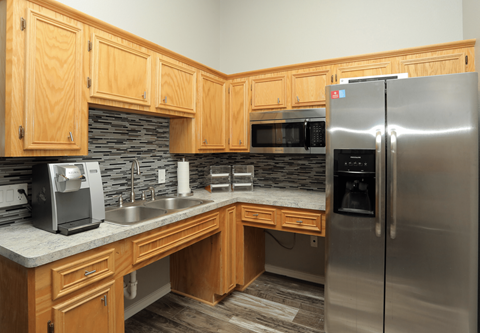 A kitchen with wooden cabinets and a stainless steel refrigerator.