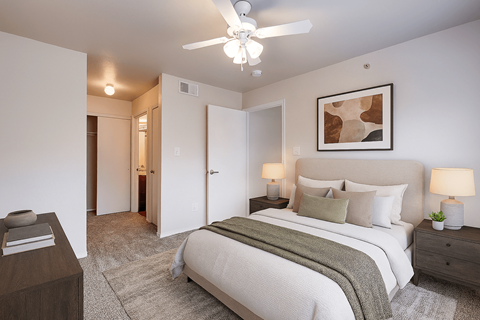 A bedroom with a large bed and a ceiling fan.