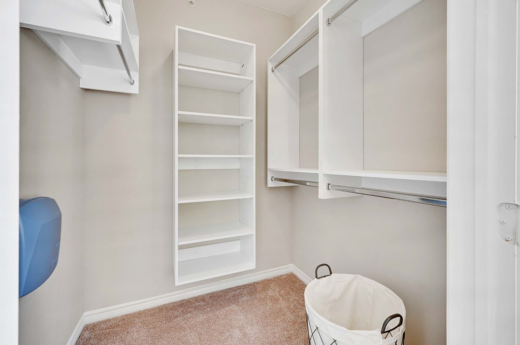 a laundry room with white cabinets and a trash can