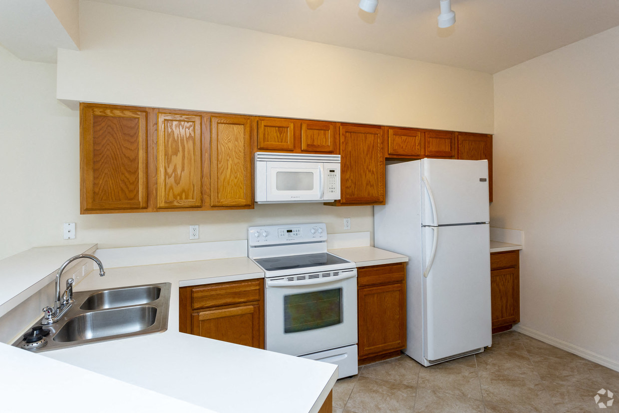 View of kitchen with oak cabinets and white appliances