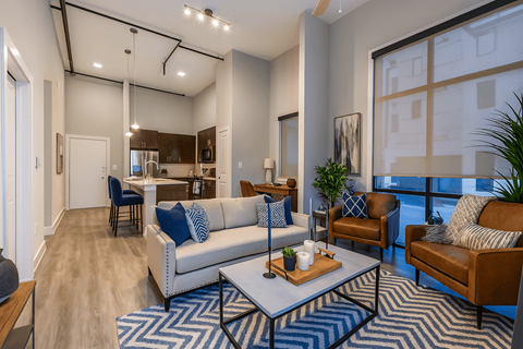 A living room with a white couch and a blue and white rug.