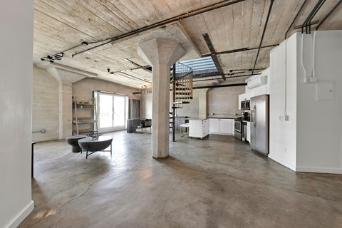 A large open space with a cement floor and a high ceiling with exposed pipes.