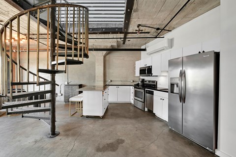 A kitchen with a spiral staircase in the middle.