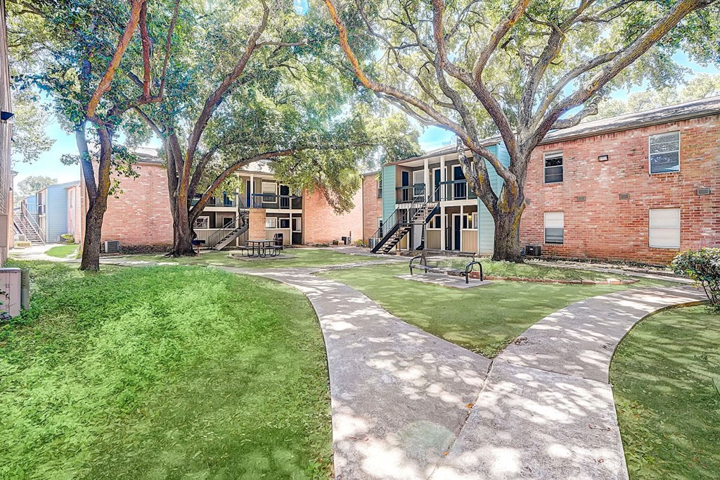 a sidewalk leading to a brick building with trees