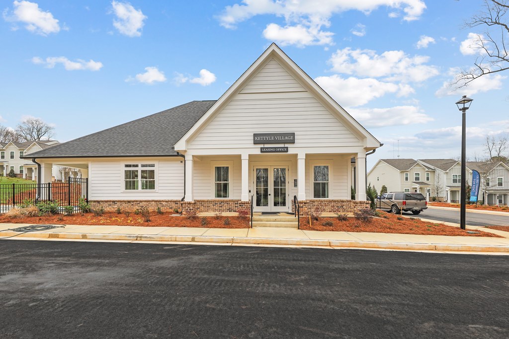 the front of a white house with a street in front of it