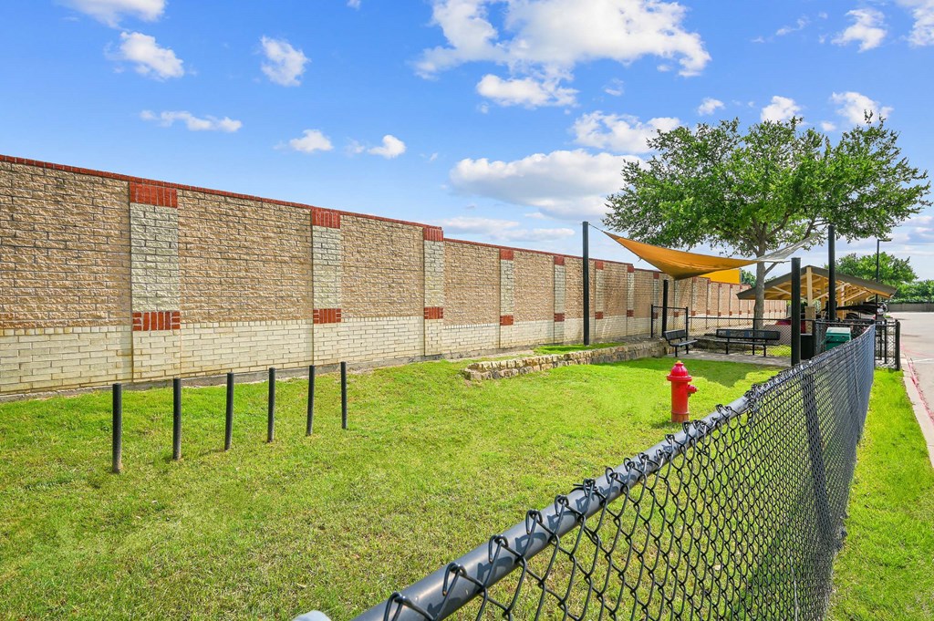 a brick wall with a chain link fence and a red fire hydrant