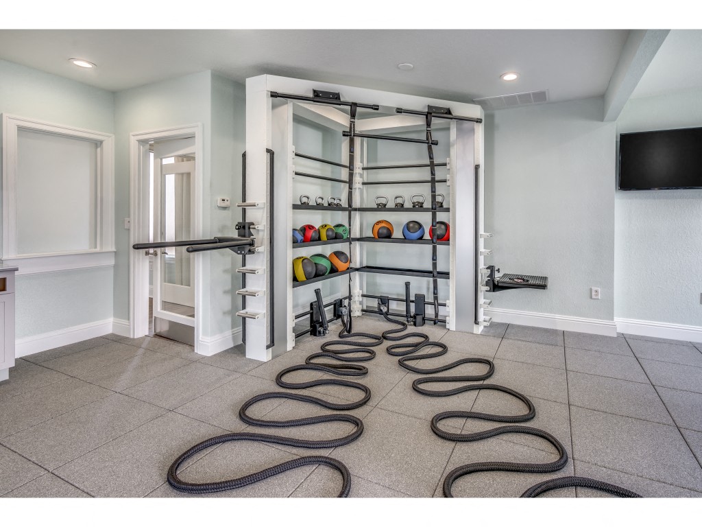 the home gym has plenty of floor space and a wall mounted tv
