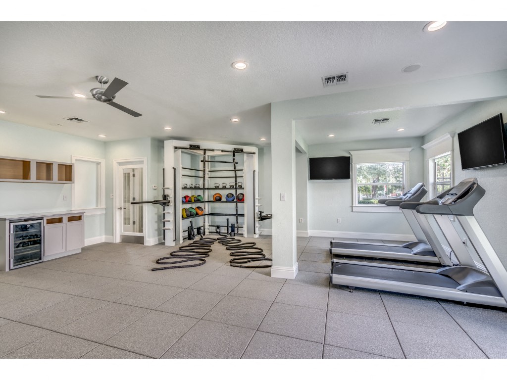 a workout room with treadmills and a tv